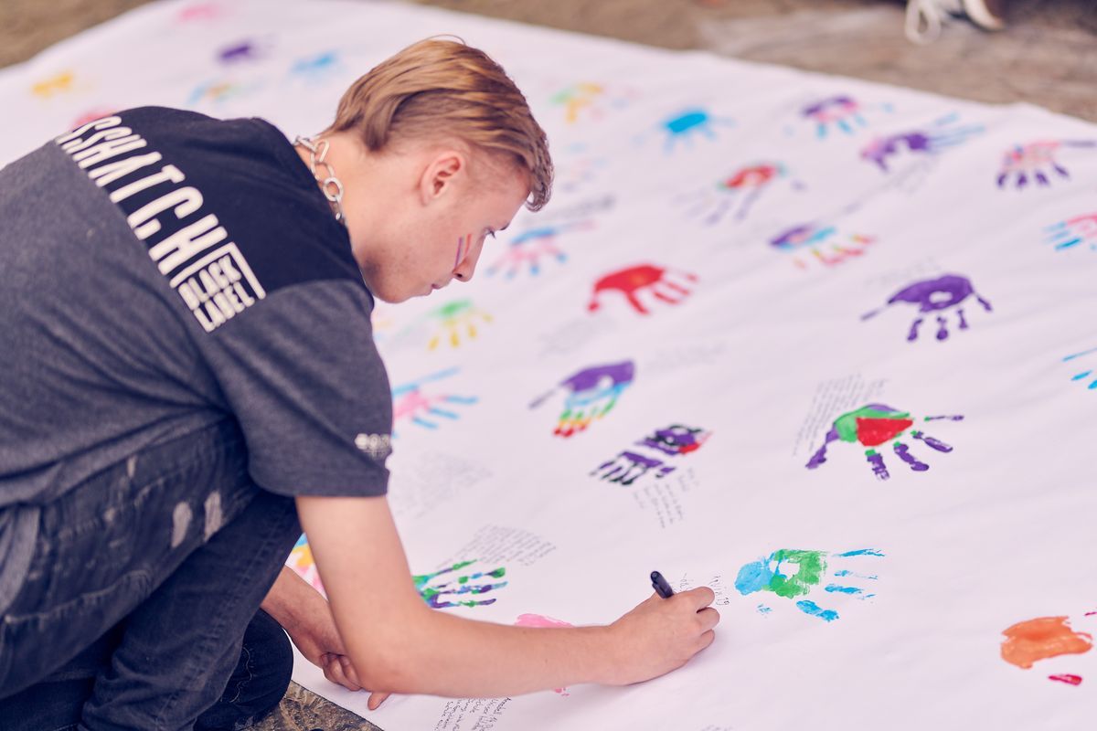 Jugendlicher beschriftet Banner mit Farbabdruck seiner Hand , Foto: Marius Steffen, www.mariussteffen.de